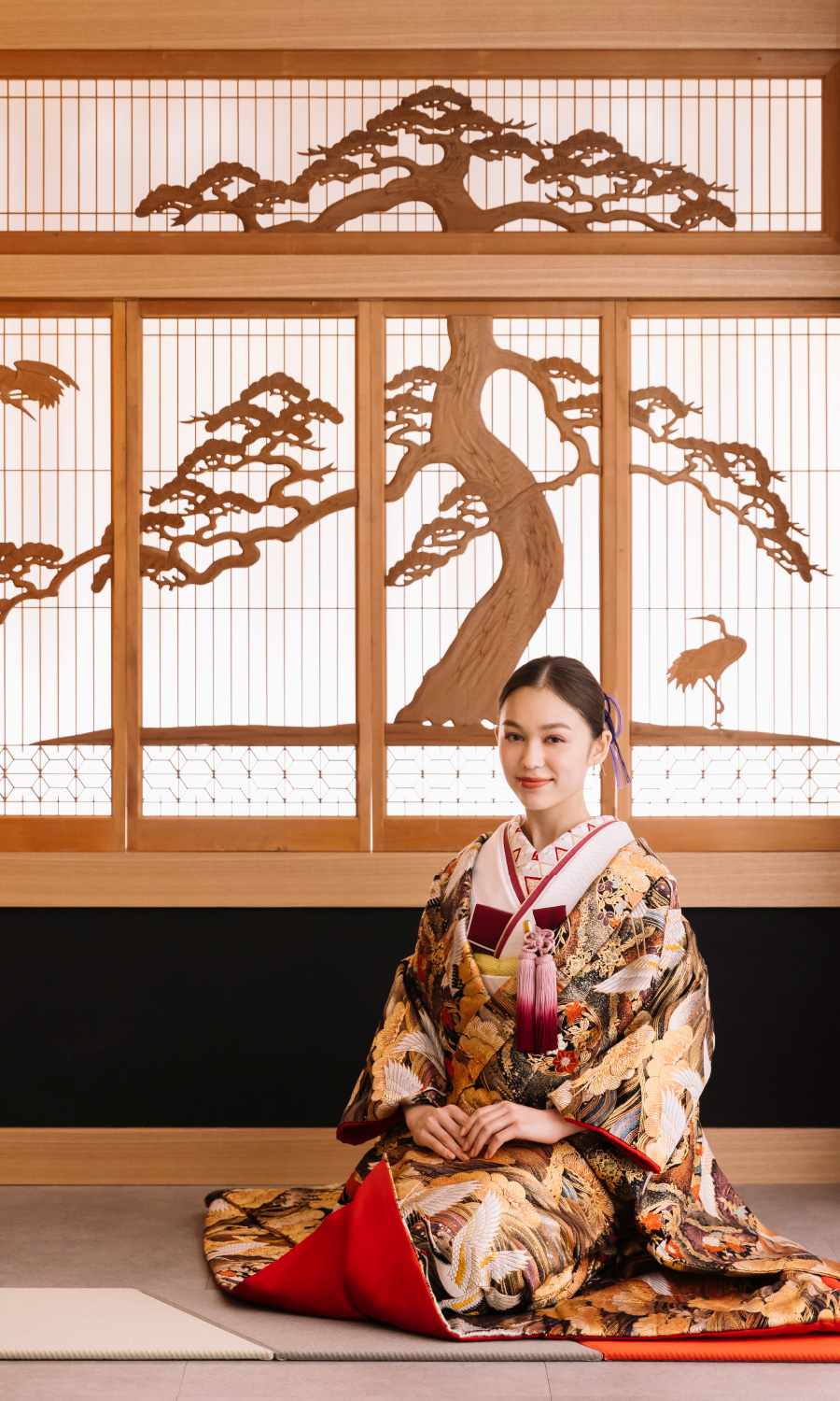 繊細な松の木細工が配置された障子をバックに正座をしている新婦様の和装ソロショット                    