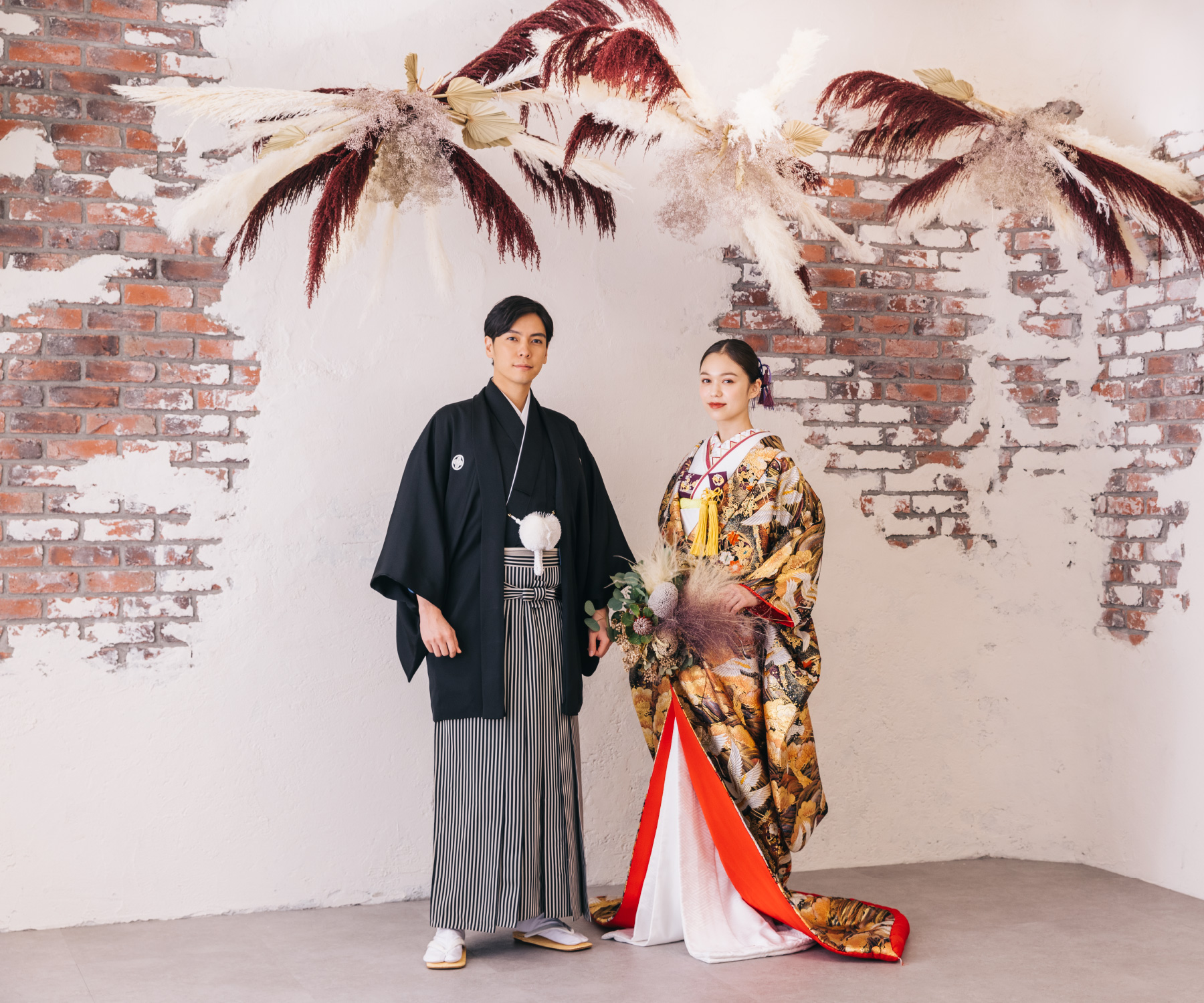 ドライフラワーとレンガを背景にした新郎新婦様の和装結婚写真                    