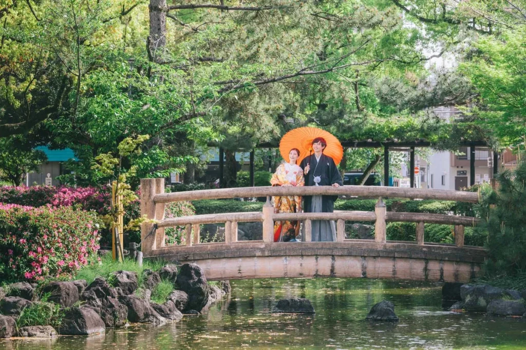 太鼓橋の上でおふたりが並んで、和傘を差しながらたたずむショット