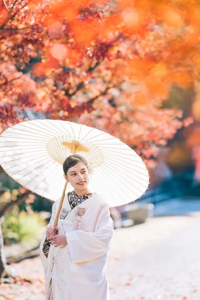 鮮やかな紅葉をバックに和傘をさす新婦様のソロショット