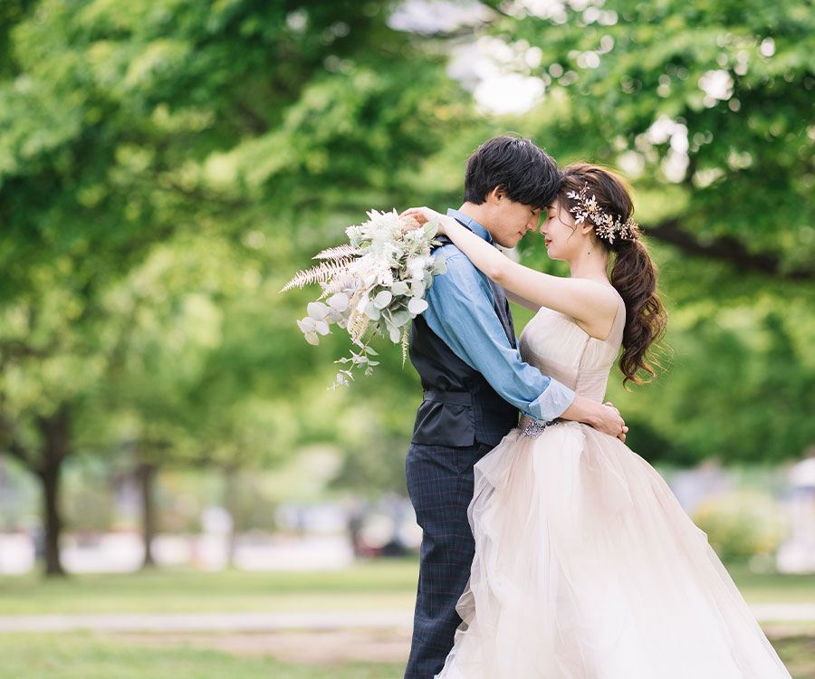 木々に囲まれながら抱き合う新郎新婦様の結婚写真