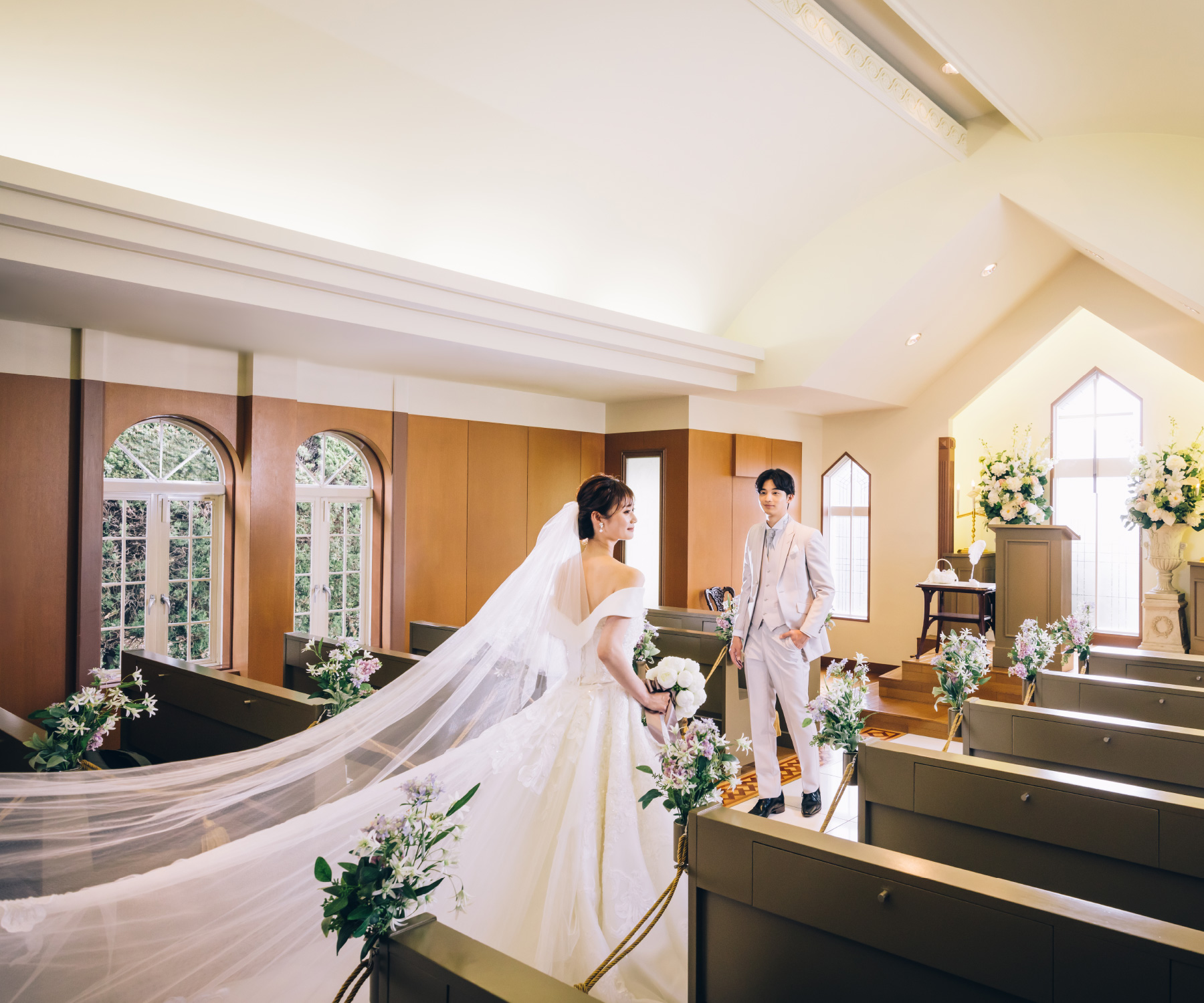 チャペルでウェディングドレスを着た新婦様を見つめる新郎様の結婚写真