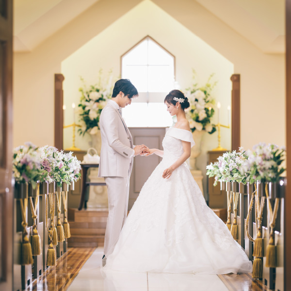 チャペルで新婦様の薬指に指輪をはめる新郎様の結婚写真