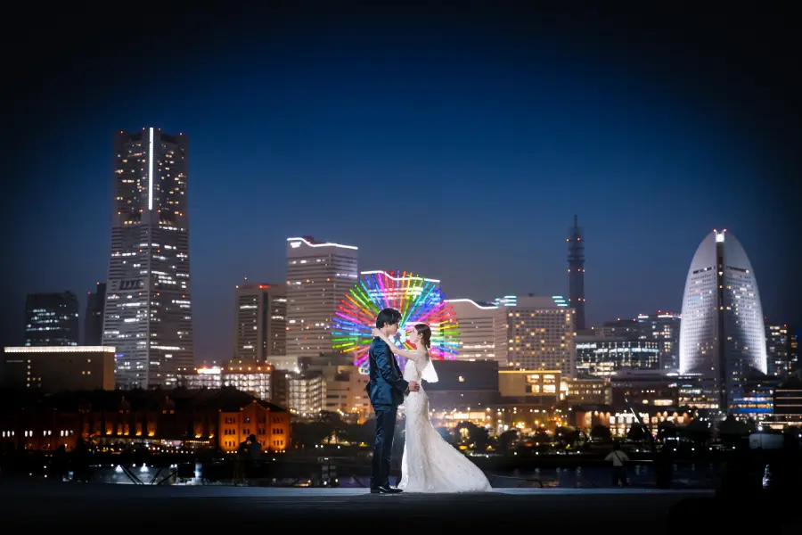 都市のネオンを背に手を取りあう新郎新婦様の結婚写真