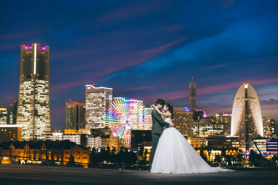 都市のネオンを背に手を取りあう新郎新婦様の結婚写真