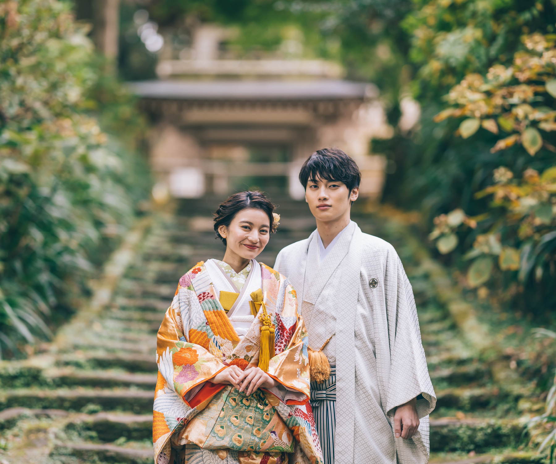 鮮やかな緑に囲まれた階段で寄り合う新郎新婦様の結婚写真