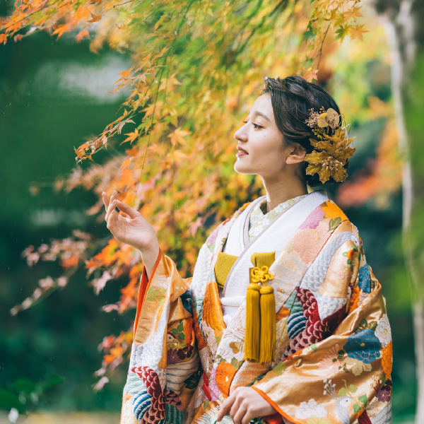 色打掛を着て紅葉に触れる新婦様のソロショット