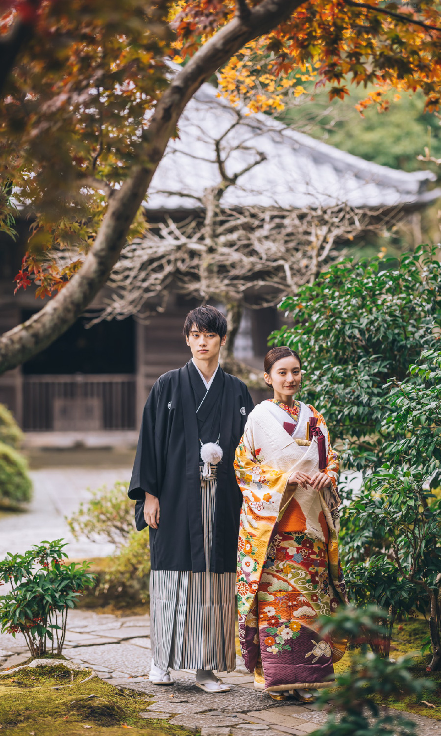 日本家屋を背景に庭園で佇む伝統的な結婚写真