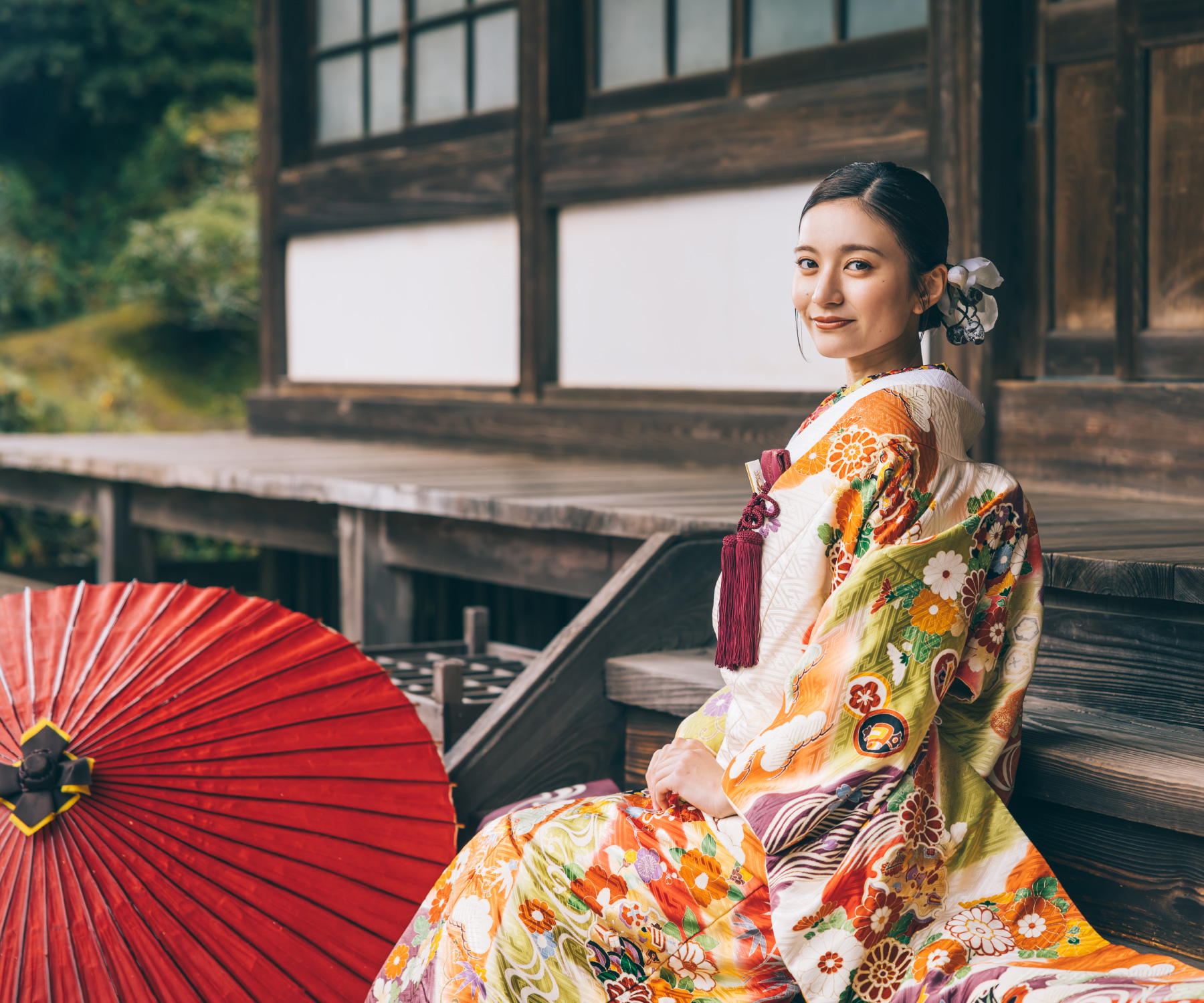 境内の階段で隣に赤い和傘を置いて佇む新婦様のソロショット