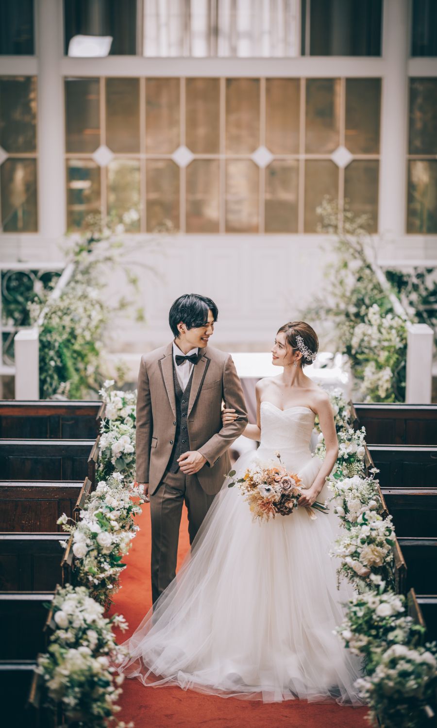 赤いカーペットが引かれた階段で見つめ合う新郎新婦様の結婚写真