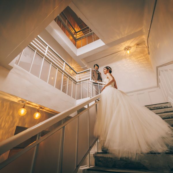 階段の手すりに触れて遠くを眺める新郎新婦様のウェディングフォト