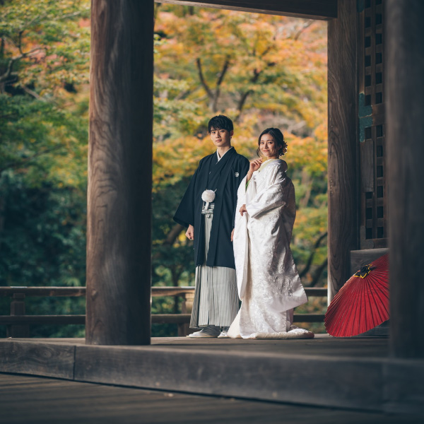 祖師堂で隣に和傘を置いて微笑む新郎新婦様の結婚写真