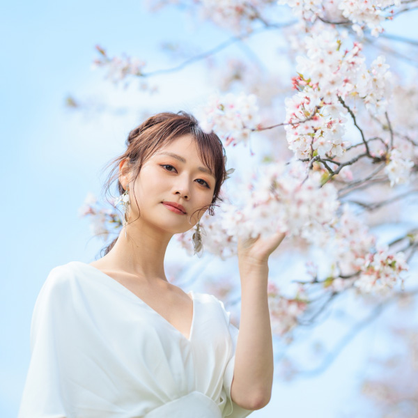 桜に触れて微笑む新婦様のソロショット