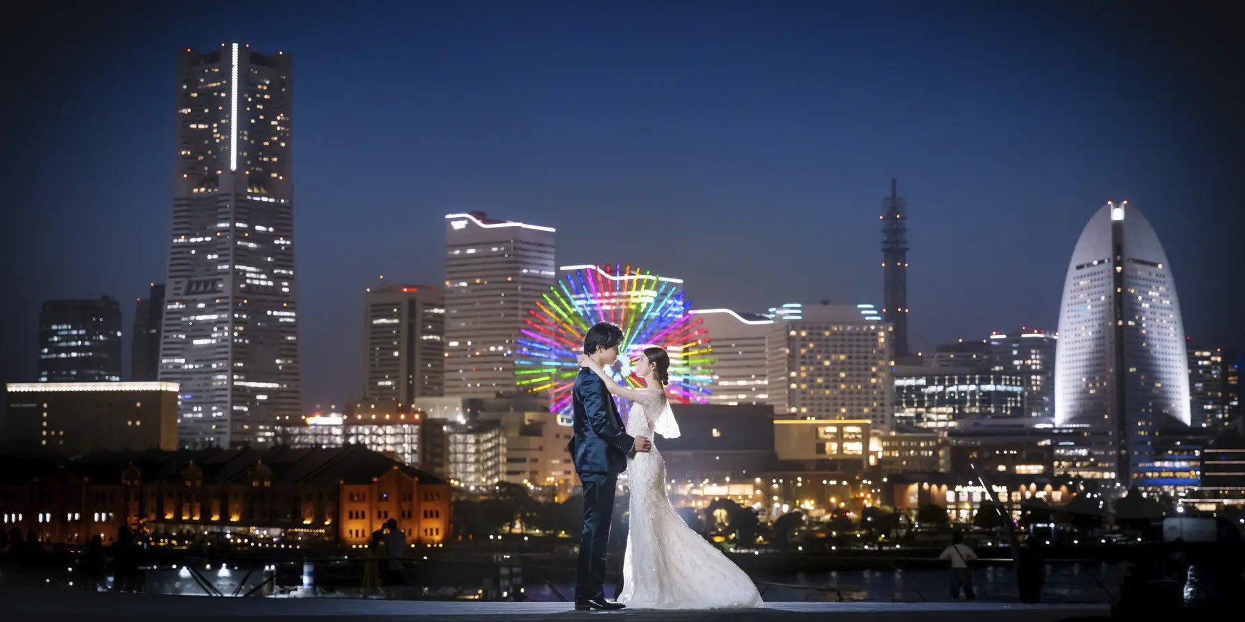 美しいみなとみらいの夜景をバックに抱き合う新郎新婦様のナイトロケーションフォト