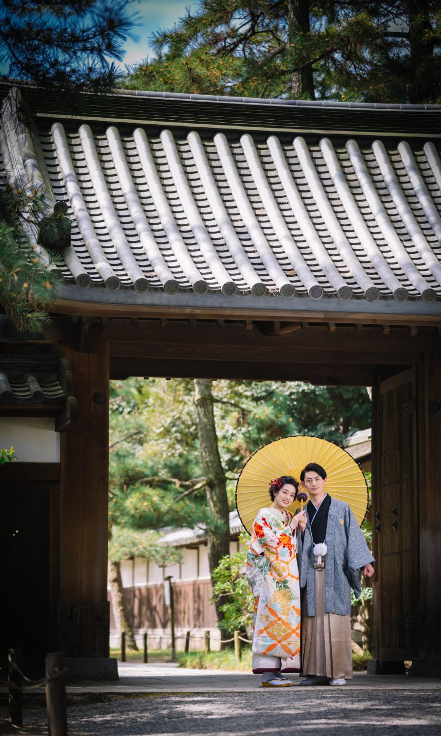 三渓園の門の下で和傘をさして微笑む新郎新婦様の和装前撮り