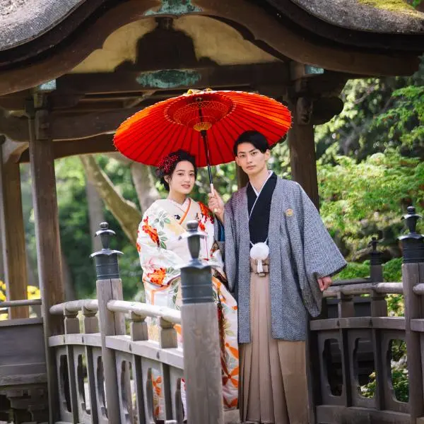 赤い和傘をさして微笑む新郎新婦様の和装前撮り