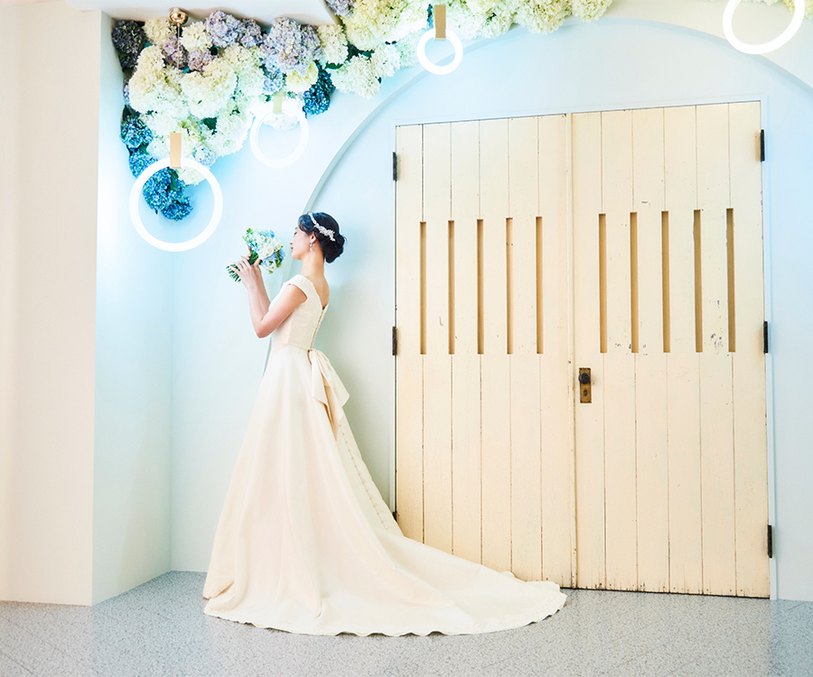      淡い青色のスタジオにウェディングドレスが映える新婦様の全身ショット               