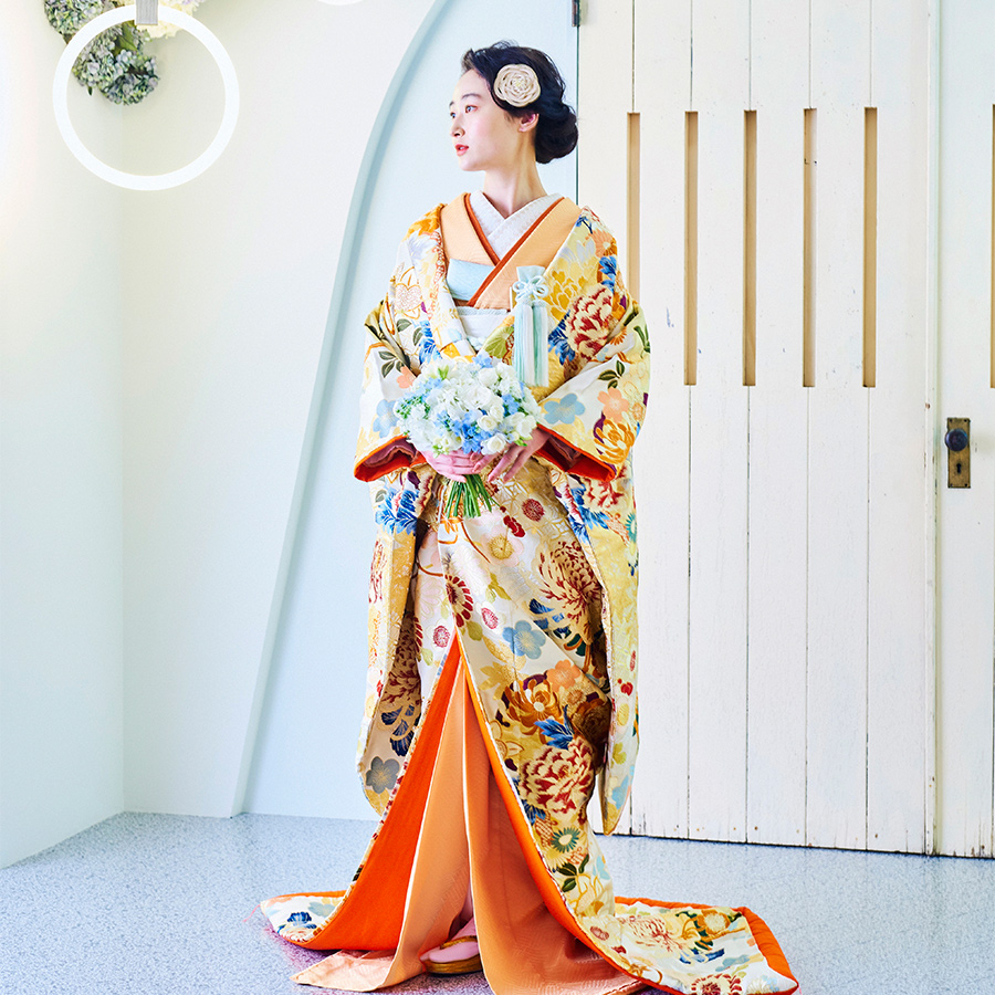      温かみのある色打掛が爽やかなブルーの背景セットに映える新婦様の和装全身ショット               