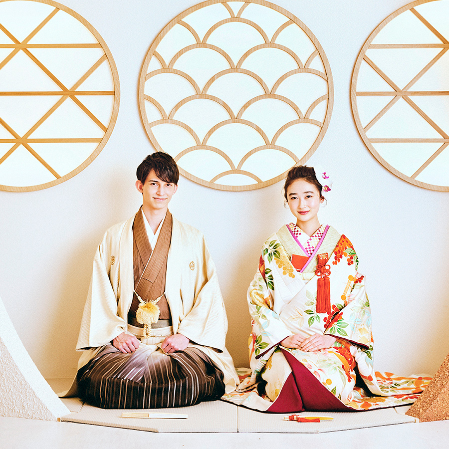 和モダンな背景セットをバックに正座をして微笑む新郎新婦様の和装前撮り