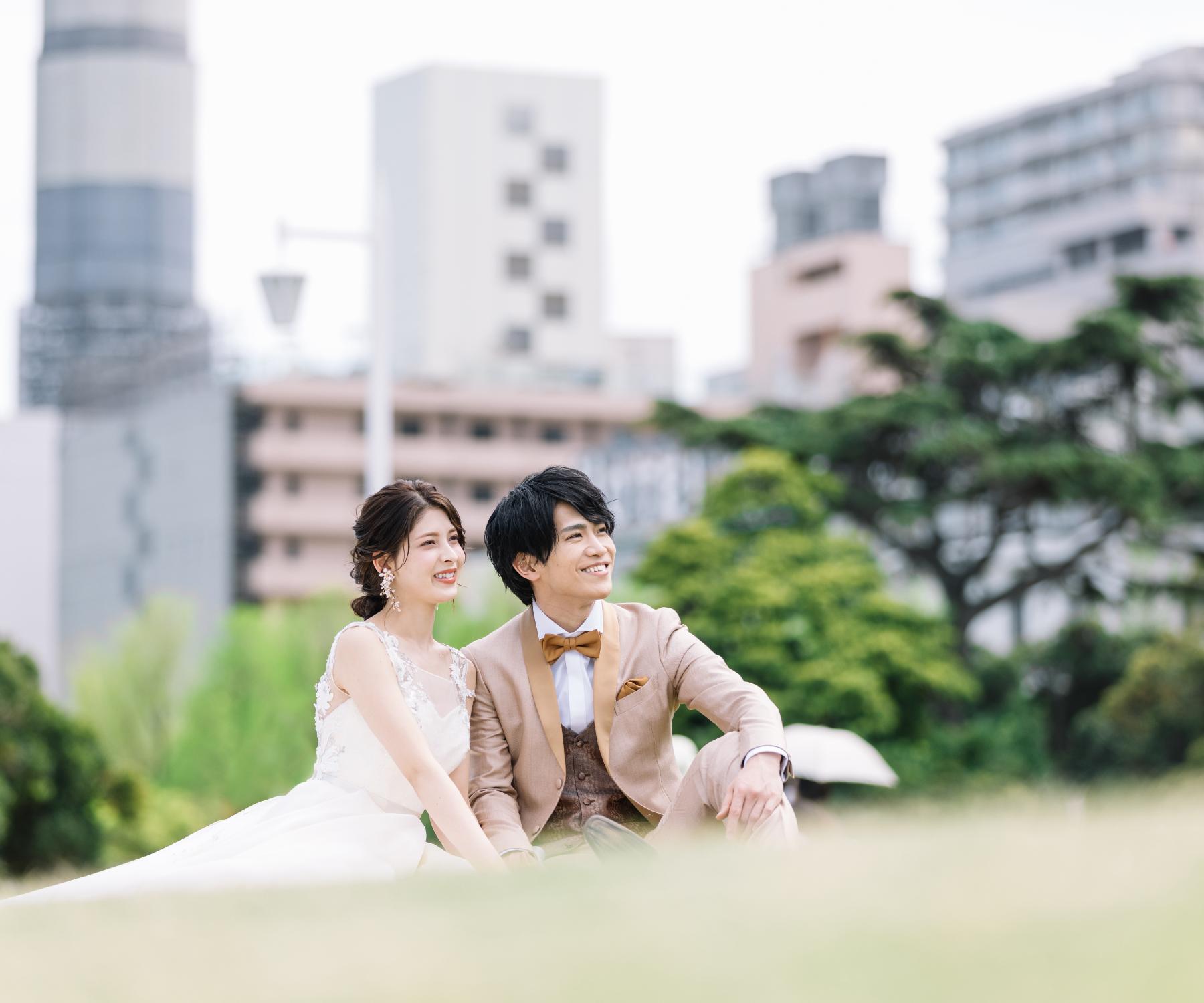 芝生公園で座って話す新郎新婦様のウェディングフォト