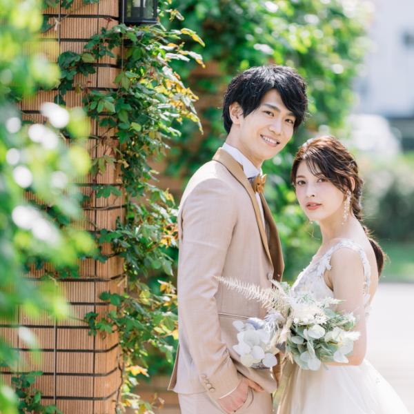 緑溢れる公園でこちらを見つめる新郎新婦様のウェディングフォト