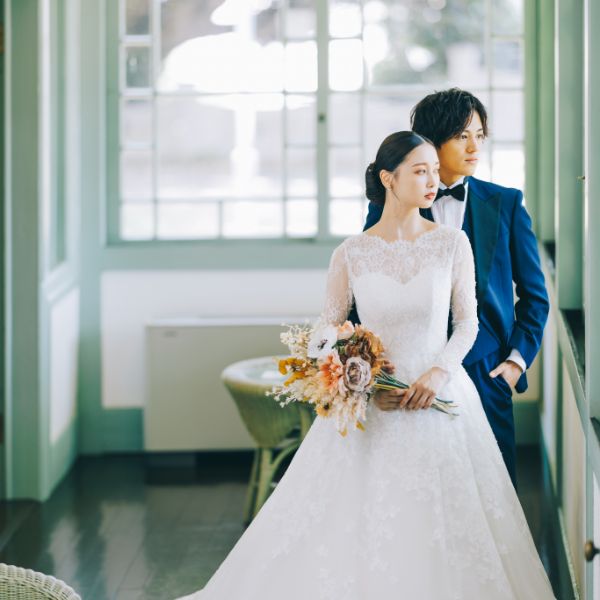 二人で窓から見える庭園を眺める結婚写真